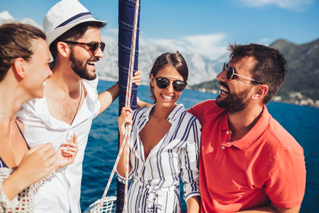 Smiling friends sailing on yacht - vacation, travel, sea, friendship and people conceptの写真素材