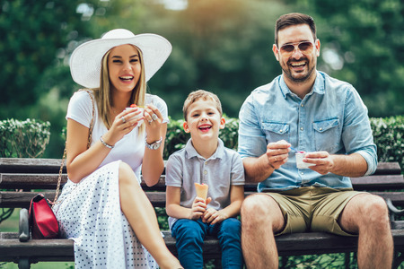 Young happy family spending their weekend in the park. They are eating the ice cream.の写真素材