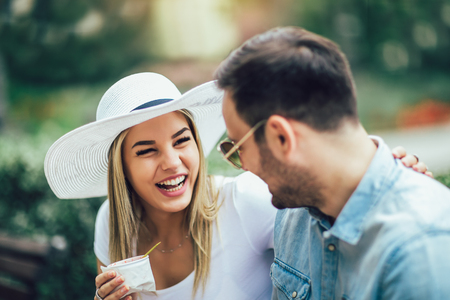 Couple joking and having fun while eating an ice cream in the park.の写真素材