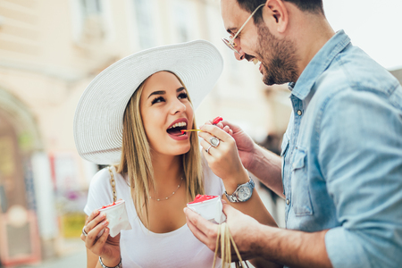 Smiling couple in shopping with ice-cream and shopping bagsの写真素材