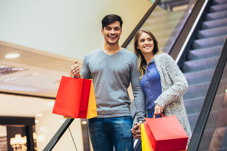 Happy young couple shopping and holding bags in shopping mallの写真素材