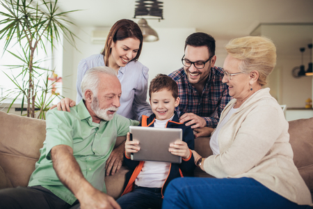 Portrait of a three generation family spending time together at home using digital tablet.の写真素材