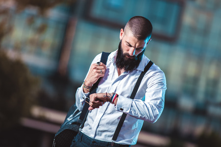 Bearded hipster businessman standing outdoor in office building background