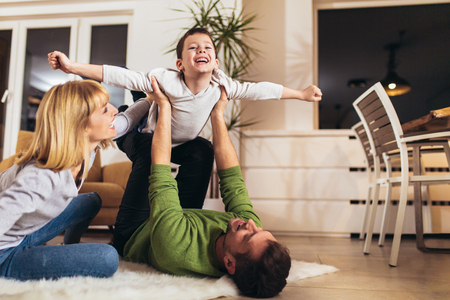 Happy family having fun on floor of in living room at home, laughing.の写真素材