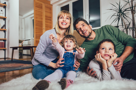 Happy family having fun on floor of in living room at home, laughing.の写真素材
