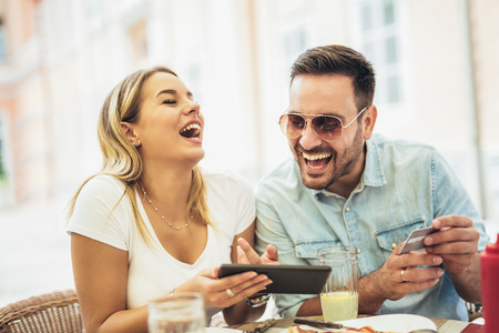 Happy young couple shopping online while sitting in a cafe.の写真素材