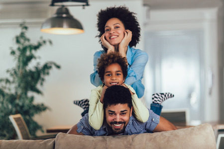 Happy family posing on the couch together at home in the living room, selective focus.の写真素材