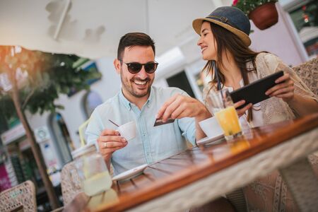 Happy young couple shopping online while sitting in a cafe.