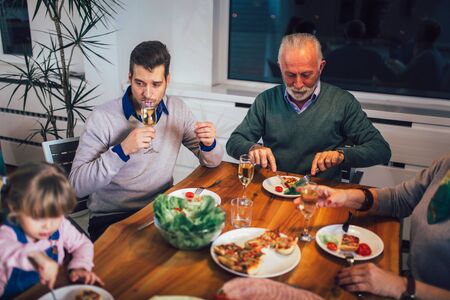 Multi generation family enjoying meal around table at homeの写真素材