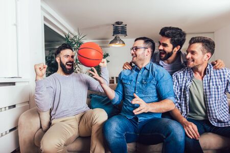 Happy friends or basketball fans watching basketball game on tv and celebrating victory at home.Friendship, sports and entertainment concept.の写真素材