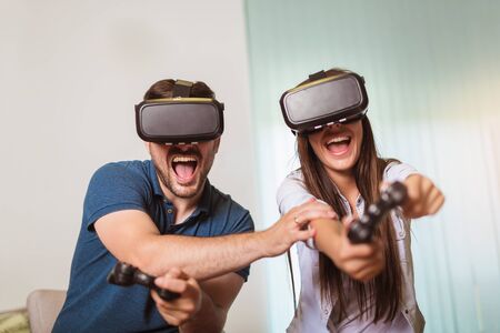 Young happy couple playing video games virtual reality glasses. Couple having fun with new trends...