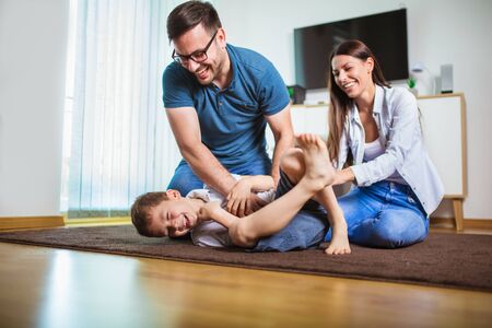 Smiling young parents and their child are very happy, they are at homeの写真素材