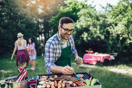 Handsome male preparing barbecue outdoors for friendsの写真素材