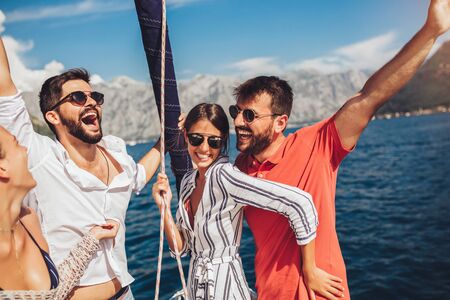 Smiling friends sailing on yacht. Vacation, travel, sea, friendship and people conceptの写真素材