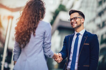 Smiling business colleagues greeting each other outdoorsの写真素材