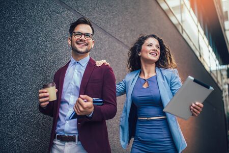 Handsome man and beautiful woman as business partners using digital tablet outdoorの写真素材