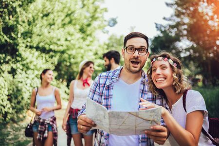 Group of smiling friends walking with backpacks in woods - adventure, travel, tourism, hike and people concept. Young Men And Women On Hike Tourists Adventure Activityの写真素材