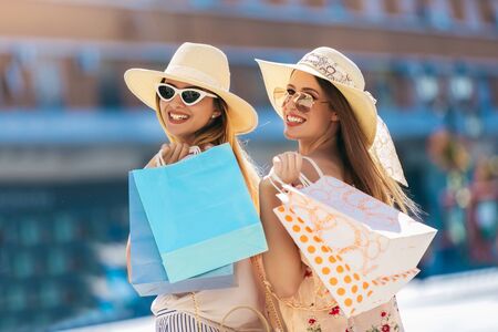Two beautiful girls in sunglasses with shopping bags in city.の写真素材