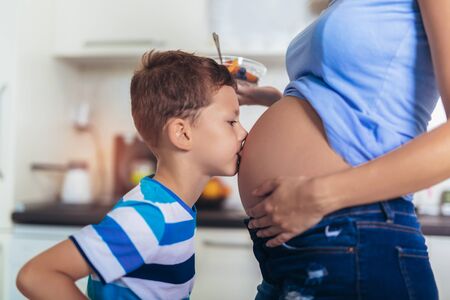Portrait of happy little boy hugging mother's pregnant belly.の写真素材