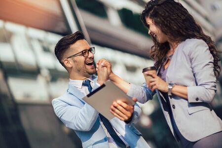 Handsome man and beautiful woman as business partners using digital tablet outdoorの写真素材