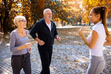 Senior man and woman and young female instructor  workout on fresh air. Outdoor activities, healthy lifestyle, strong bodies, fit figures. Stylish, modern sportswear.の写真素材