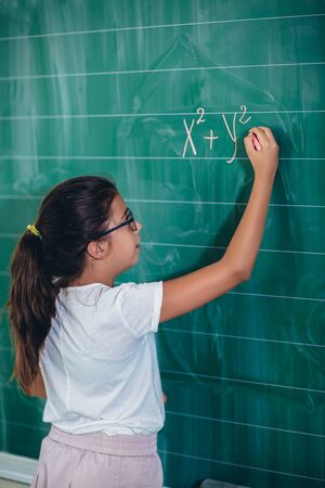 Happy schoolchild writing on blackboard