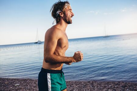 Running man jogging on beach. Male runner training outside working out.の写真素材