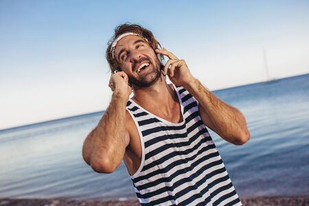 Portrait of athletic man with fit muscular body resting after jogging on beach.の写真素材