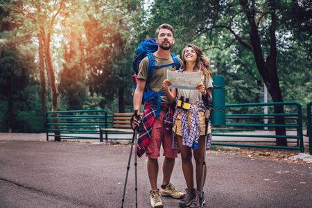 Smiling couple walking with backpacks over natural background