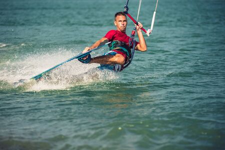 Professional kiter makes the difficult trick on a beautiful background. Kitesurfing Kiteboarding...