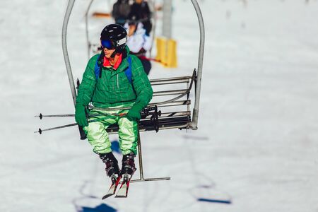 Skier wearing skis, helmet and mask sitting in ski lift cabinの写真素材