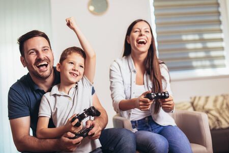 Smiling family sitting on the couch together playing video games