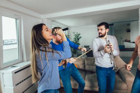Group of friends playing karaoke at home. Concept about friendship, home entertainment and people