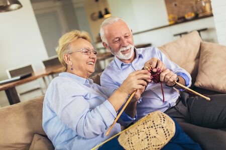 Senior woman teaching her husband the art of knitting woollen clothes.の写真素材