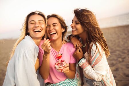 Girls eating ice cream on the beach, selective focus.