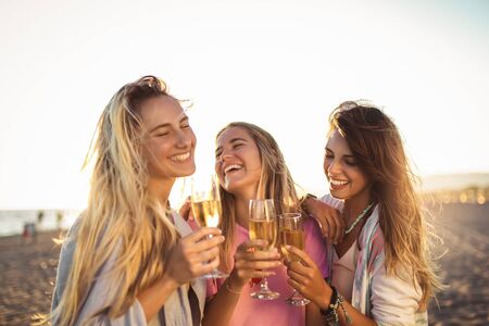 Friends having fun with champagne at celebration on beach, selective focus.の写真素材