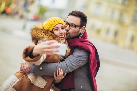 Young beautiful couple with Santa hats make selfie photo in the city.の写真素材