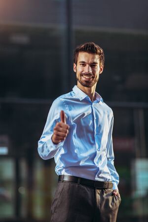 Young handsome businessman showing thumbs up outdoor.