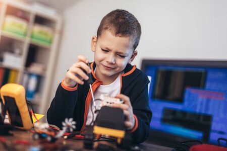 Happy smiling boy constructs technical toy. Technical toy on table full of details