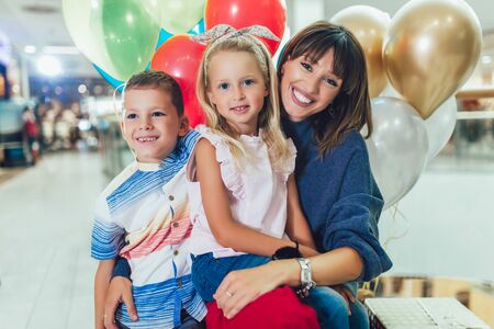 Young mother with children having fun in shopping mall.