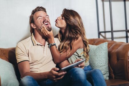 Flirting couple in cafe using digital tabletの写真素材