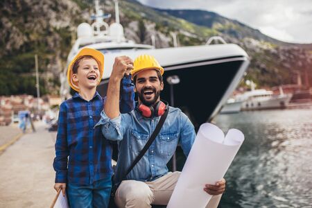 Harbor engineer with his son holding the paper, construction work, smiling.の写真素材