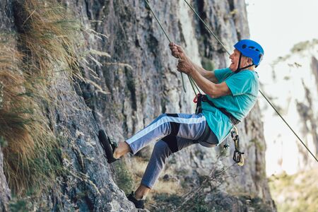 Senior man with a rope climbing on the rock.の写真素材
