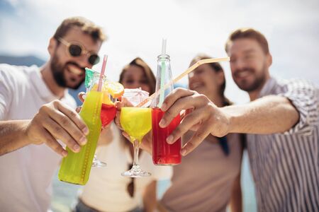Friends at the beach drinking cocktails having fun on summer vacationの写真素材