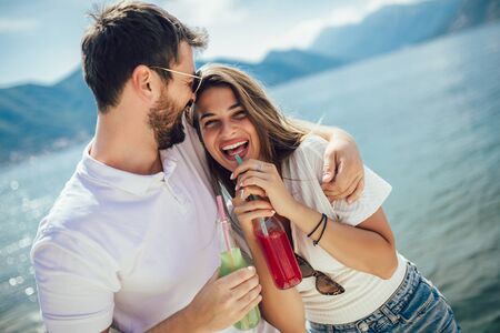 Young couple eating fruit on the beach- summer party with friends and healthy food conceptの写真素材