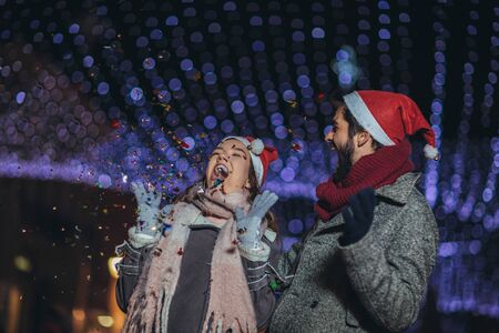 Young loving couple burning sparklers by holiday illumination on new years eve.の写真素材