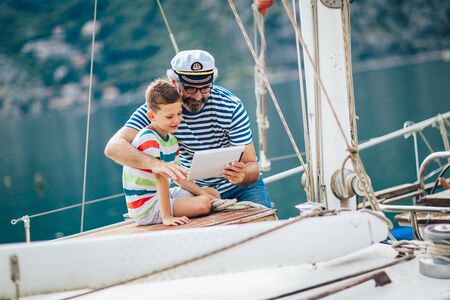 Grandfather and grandson are looking tablet on yacht sail boat.の写真素材