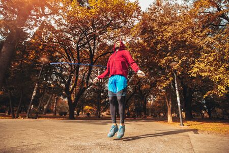 Man jumping rope outdoors on sunny autumn morning.