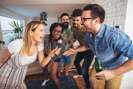 Happy friends singing together at home. Karaoke party conceptの写真素材