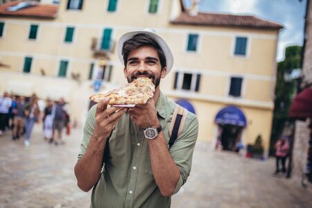 Happy man eating pizza on street.の写真素材